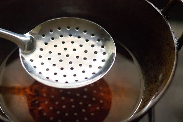 perforated ladle over the wok filled with oil