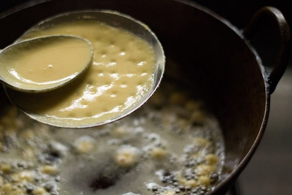 batter on perforated ladle being spread with spoon