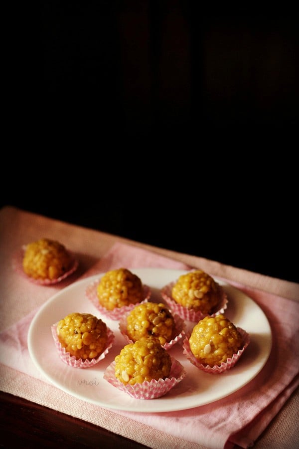 six boondi ladoo in pink muffin liners on a white plate placed on pink napkin