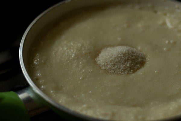 adding sugar to the burfi mixture.