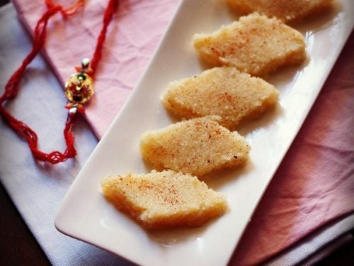 coconut burfi slices on a white platter with a rakhi in the background.