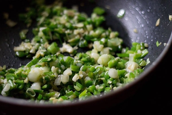 ginger, garlic, spring onions, green capsicum and green chilies in a pan