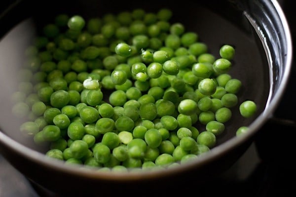 cooking green peas in water till almost done. 