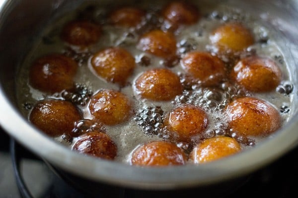 sugar syrup with gulab jamun being simmered