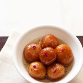 gulab jamun served in a white bowl on a white napkin