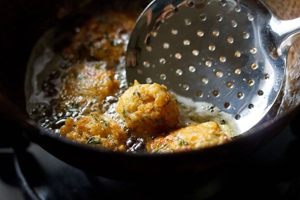 removing fried leftover rice pakora with a slotted spoon. 