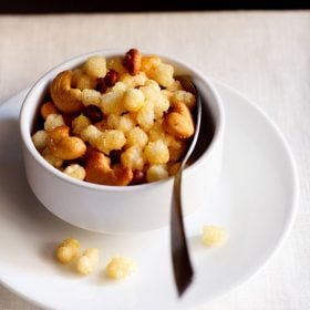 sabudana chivda served in a white bowl with a spoon in it and kept on a white plate.