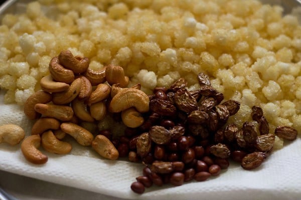 fried nylon sabudana pearls, fried peanuts, fried cashews and fried raisins placed on kitchen paper napkin. 