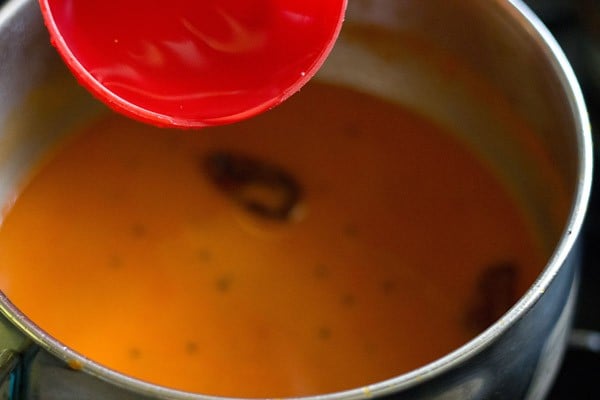 adding water to the tomato curry in pan. 