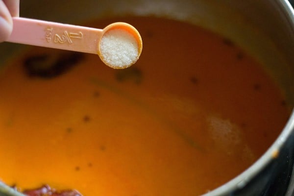 adding salt to the tomato curry in pan. 