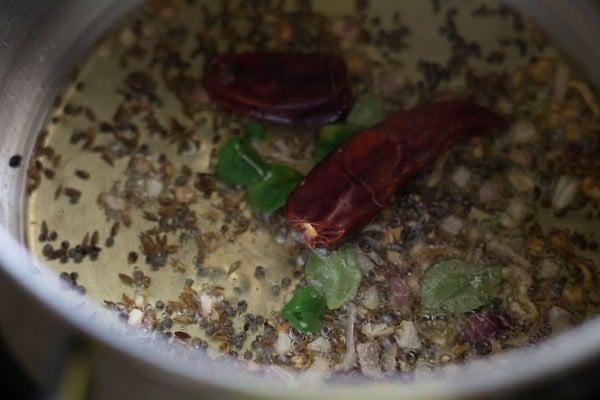 curry leaves, dried red chilies and asafoetida added to the onion-spice mixture in oil. 