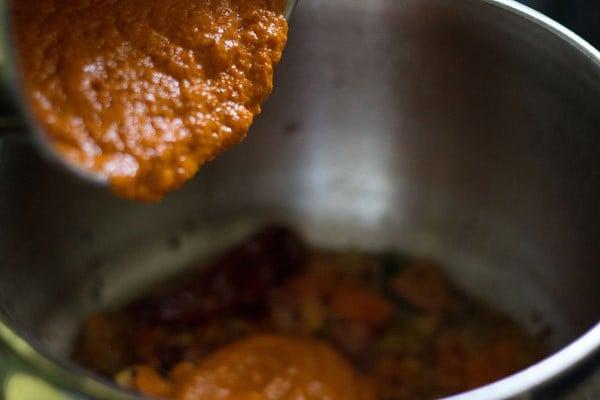 adding prepared paste to the onion-tomato mixture in pan. 