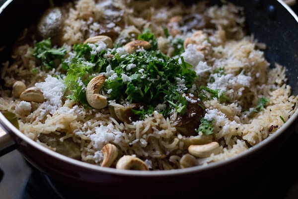 garnishing the cooked vangi bath with grated fresh coconut, chopped coriander leaves and roasted cashews. 