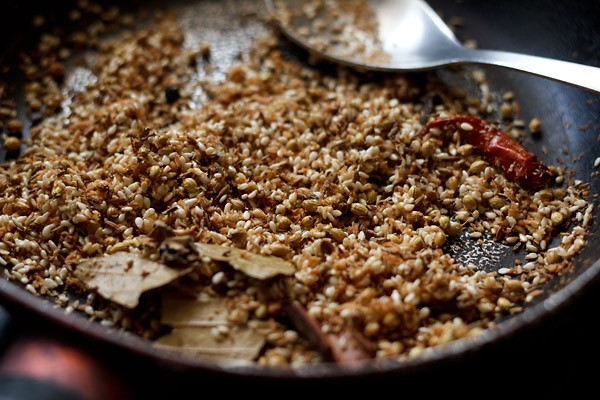 stirring dry roasting spices, coconut and sesame seeds with a spoon. 