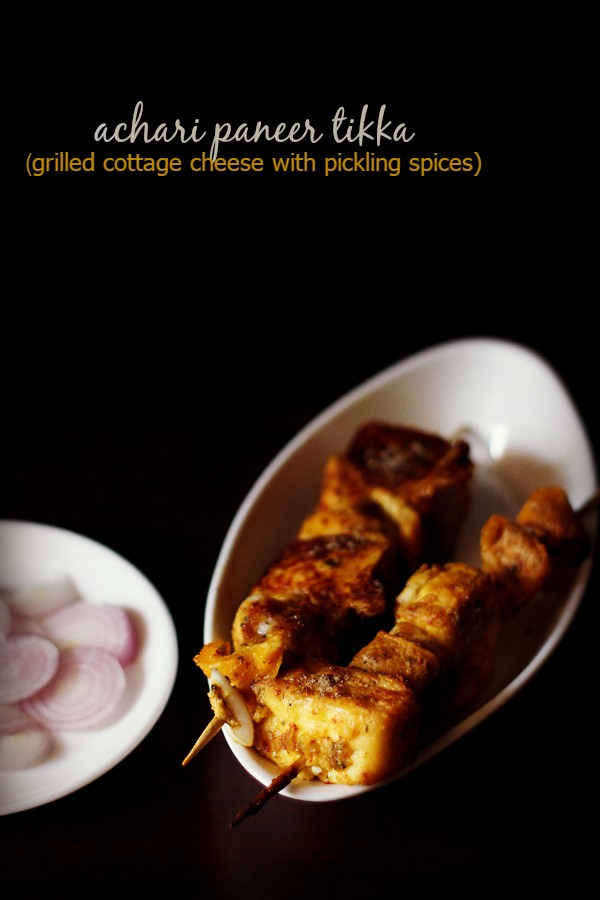 achari paneer tikka served in a white plate with onions