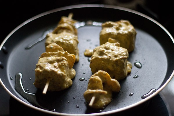 threaded paneer cubes with the skewers on the pan