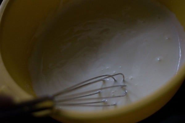 hung curd in a bowl with wired whisk