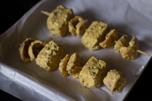 marinated and threaded paneer cubes in a baking tray