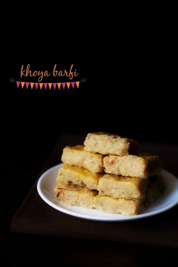barfi squares stacked on top of one another and served on a white plate. with text layover.