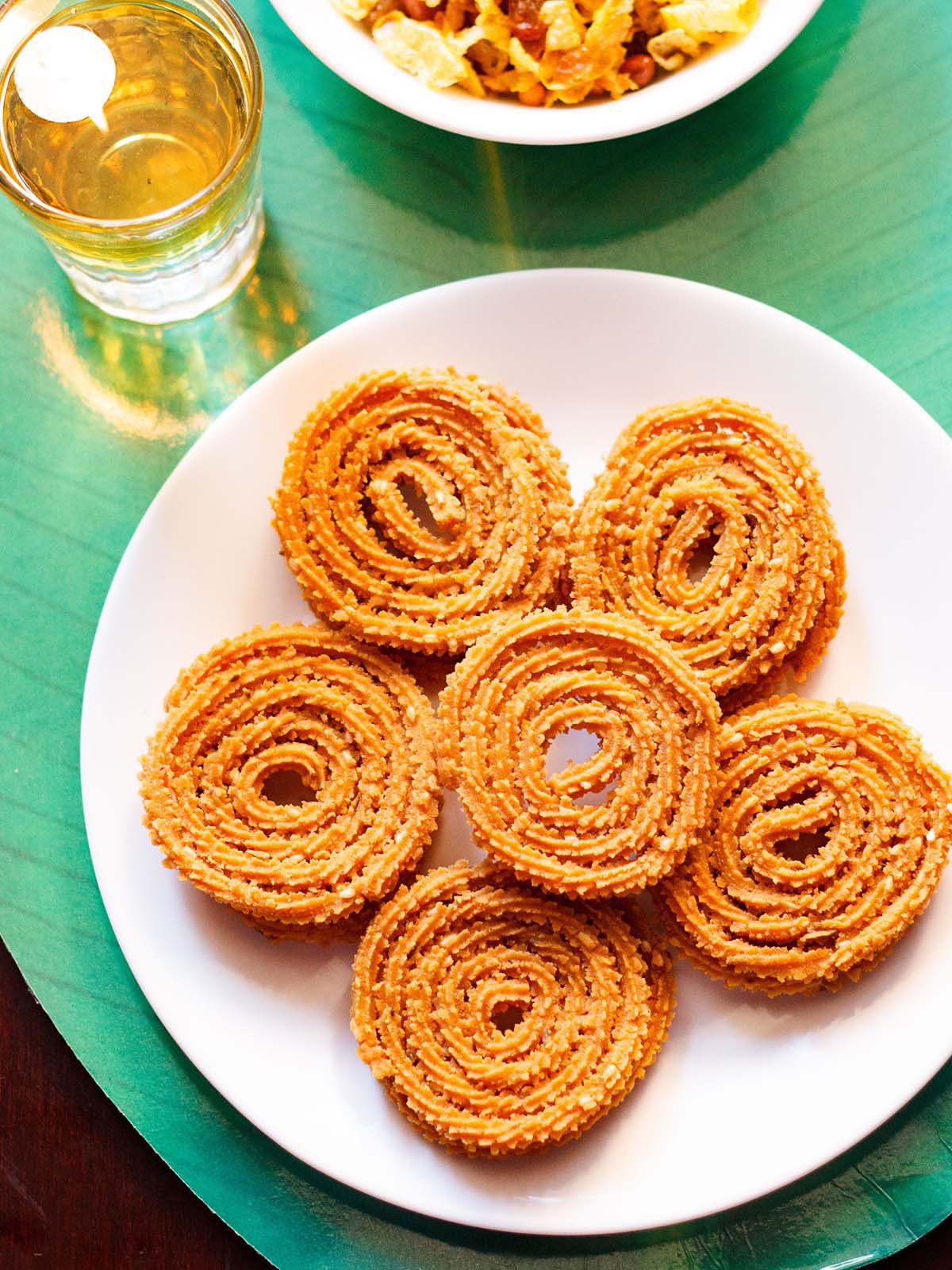 fchakli kept in a round circle with a chakli in the center on a white plate on a green background