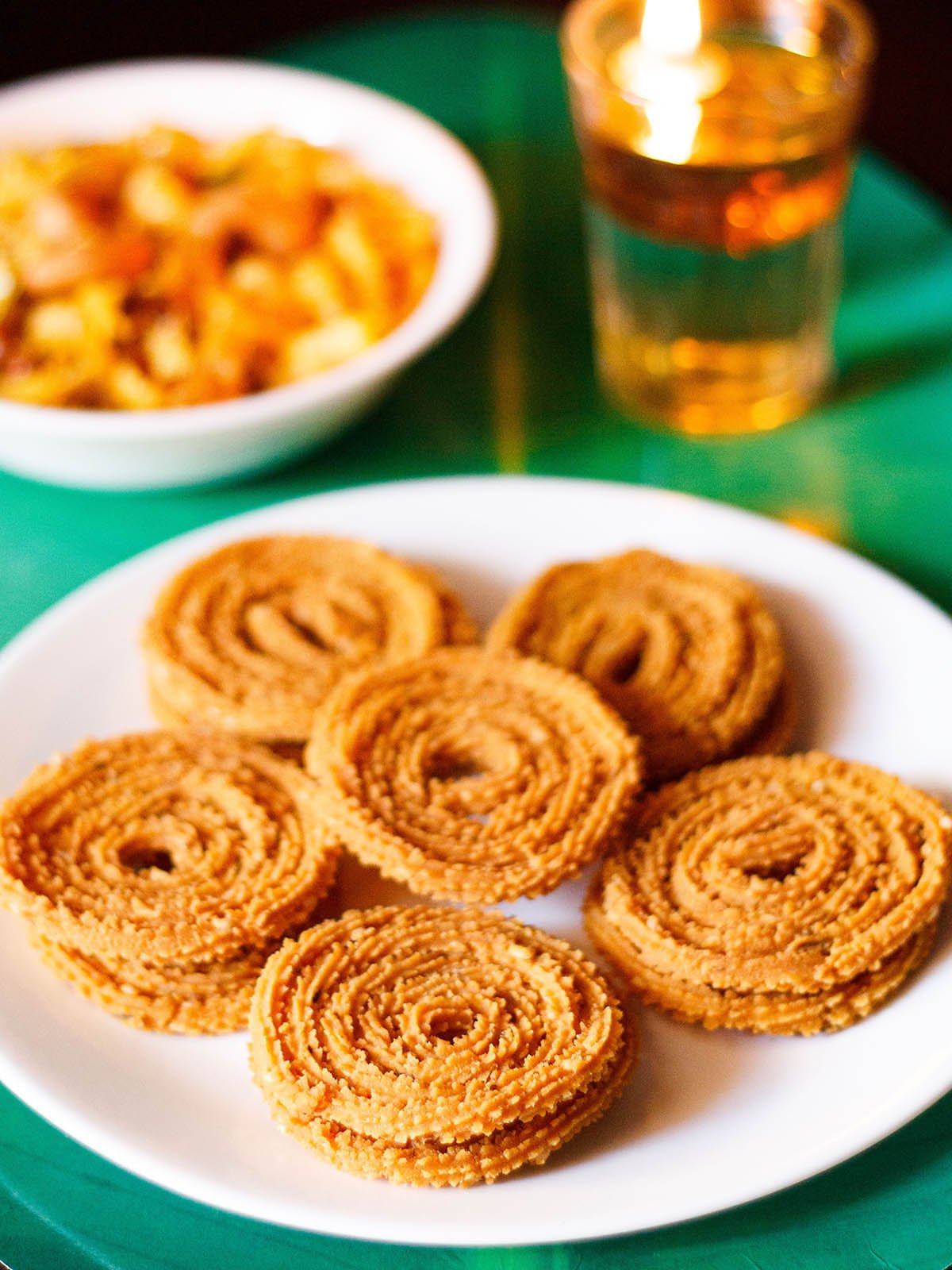 chakli served in a circle with a center chakli on a white plate with a green background