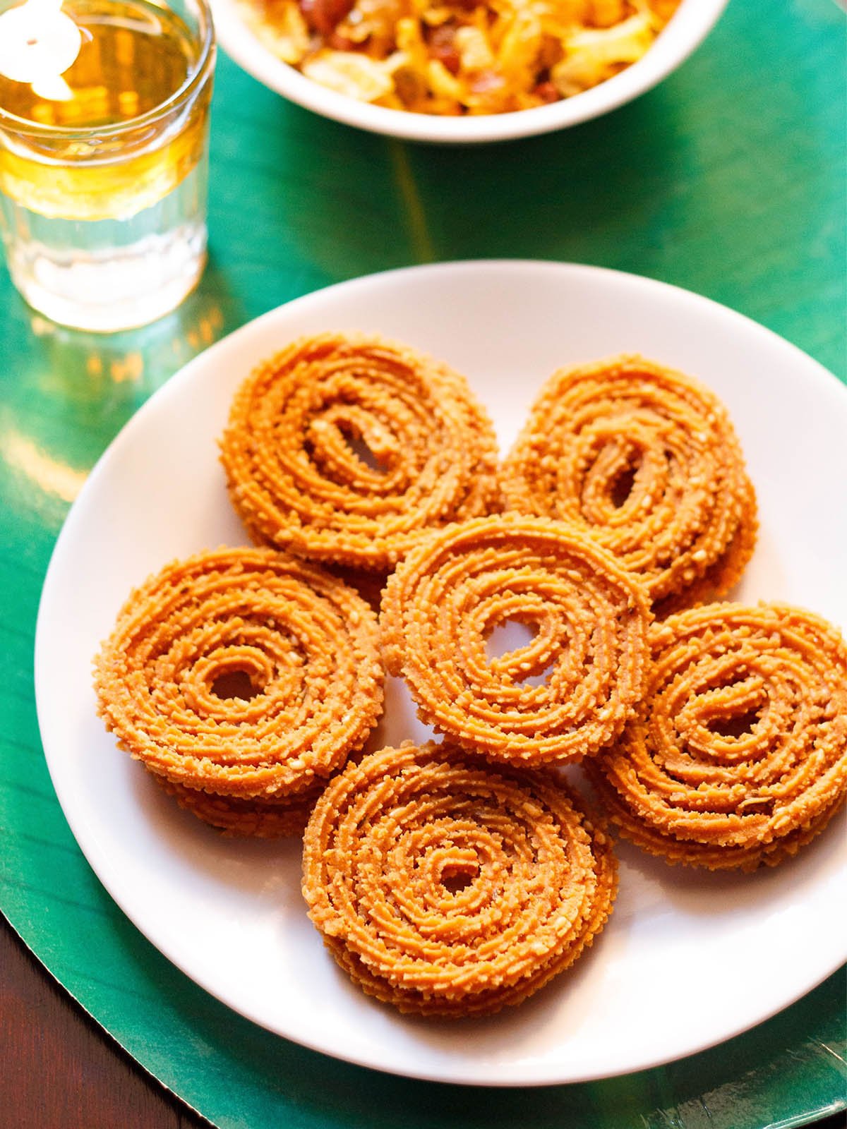 chakli served in a circle with a center chakli on a white plate with a green background