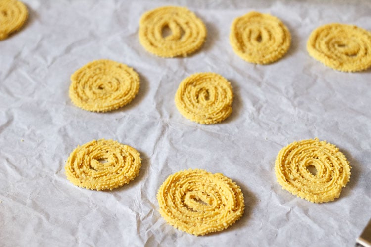 shaped chakli dough in spirals on parchment paper