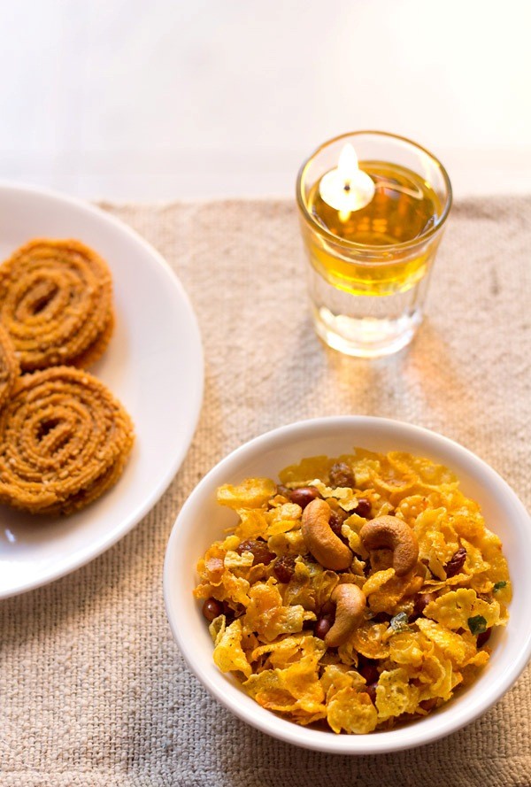 cornflakes chivda served in a white plate with a plate of murukku kept on the left side. 