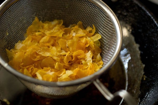 cornflakes added in a fine sieve ladle for making makai chivda. 