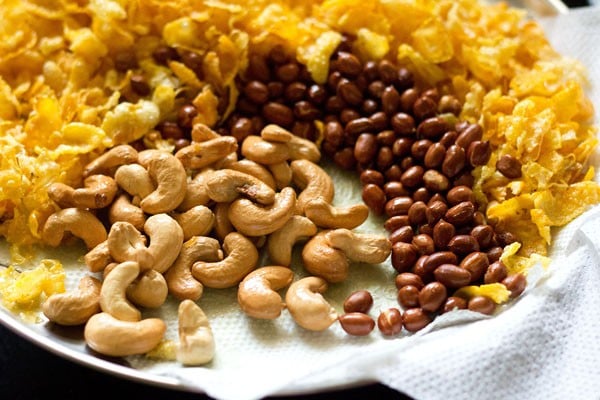 Fried cashews are served on a kitchen towel along with fried peanuts and fried tortilla chips. 