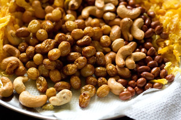 Fried raisins are served on a kitchen towel with fried cashews, fried peanuts and fried tortilla chips. 