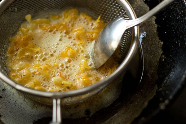 Fry the tortilla chips in hot oil, stirring with a spoon, for making makai chivda. 