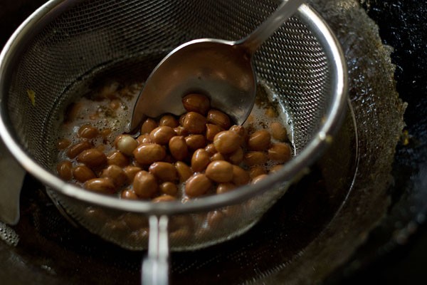 peanuts added to fine sieve ladle for making makai chivda. 