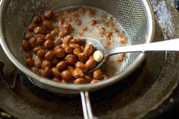 Fry the peanuts and stir with a spoon for making makai chivda. 