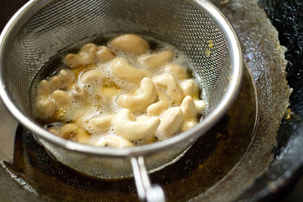 cashews added to fine sieve ladle for making cornflakes chivda. 