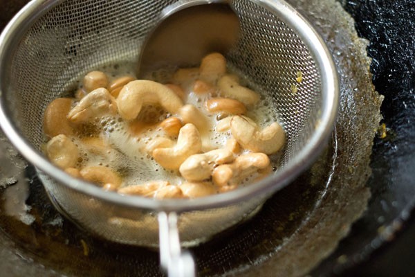 frying cashews, stirring with a spoon, for making cornflakes chivda. 