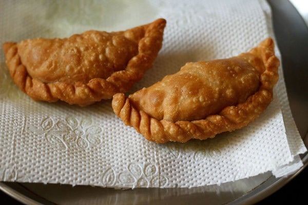 two crisp golden gujiya placed on kitchen paper towels