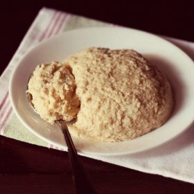 homemade khoya mawa served on a white plate with some in the spoon kept on the left side.