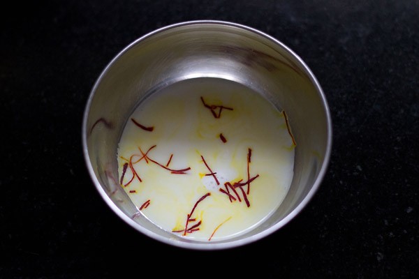 dissolving saffron strands in milk for barfi recipe. 