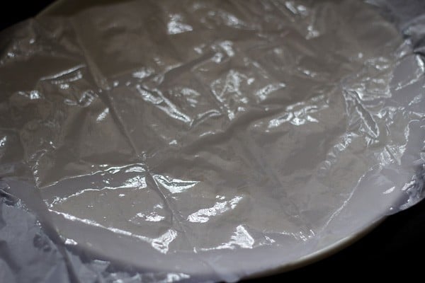 tray lined with butter paper and greased with ghee for barfi recipe. 