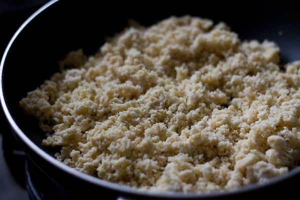 grated khoya added in a pan for khoya burfi. 