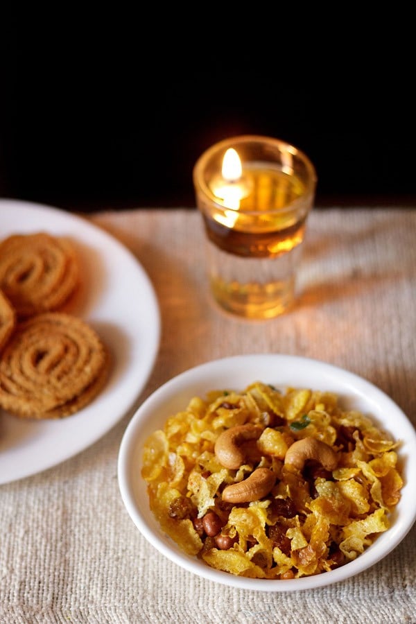 The nacho chivda was served on a white plate with a plate of Murukku on the left.