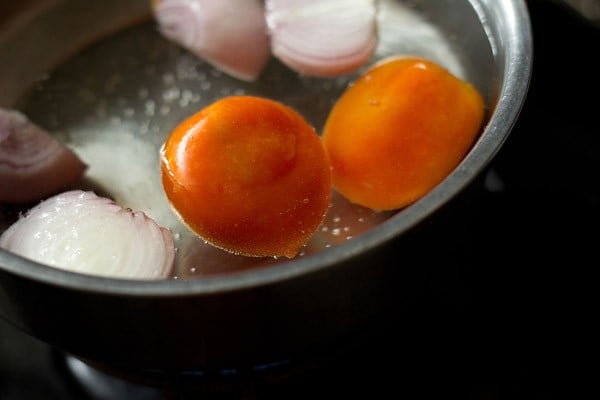 onions and tomatoes being blanched on hot water in a steel bowl