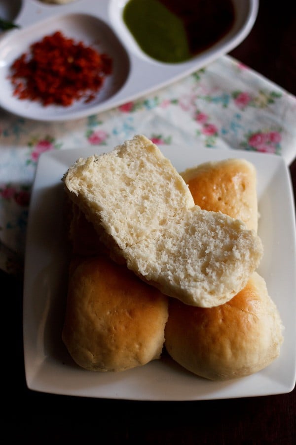 pav served on a white plate with garlic chutney, green chutney and tamarind chutney kept in the background. 