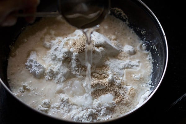 adding warm water to bowl for making ladi pav. 