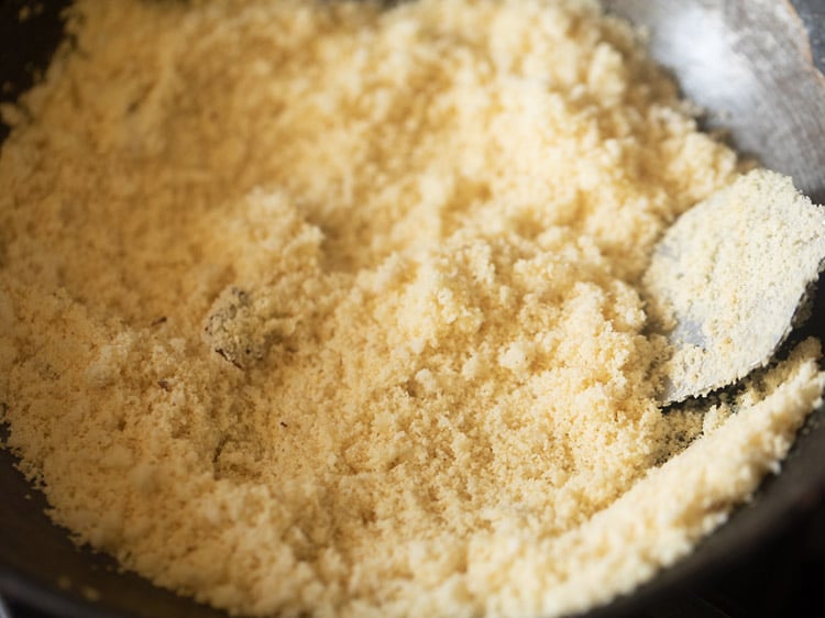 mixing and roasting rava with coconut for rava laddu recipe. 