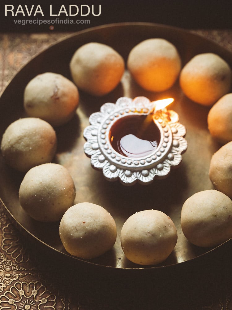 rava ladoo in a circle with lit earthern lamp in center on a bronze plate