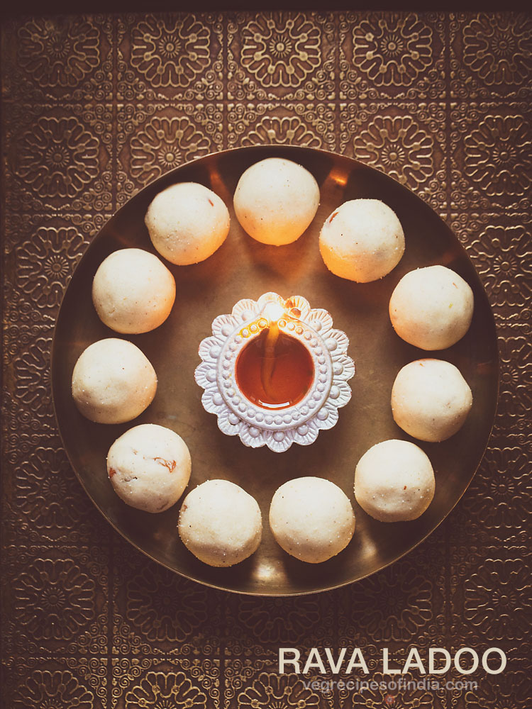 rava ladoo in a circle with lit earthern lamp in center on a bronze plate