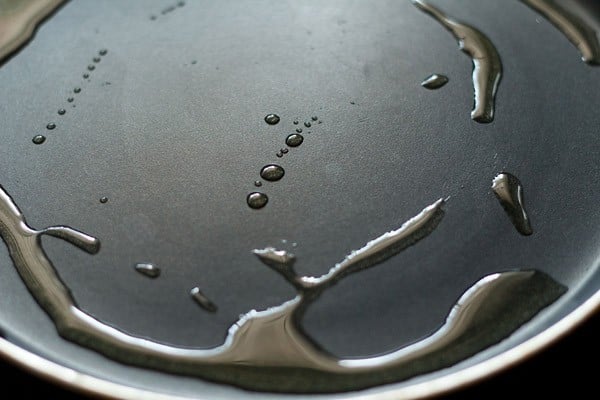 heating oil on a tawa for frying besan toast. 