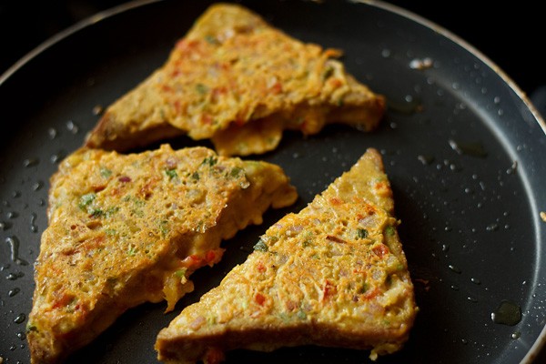 frying besan bread toast till evenly cooked and browned from both sides. 